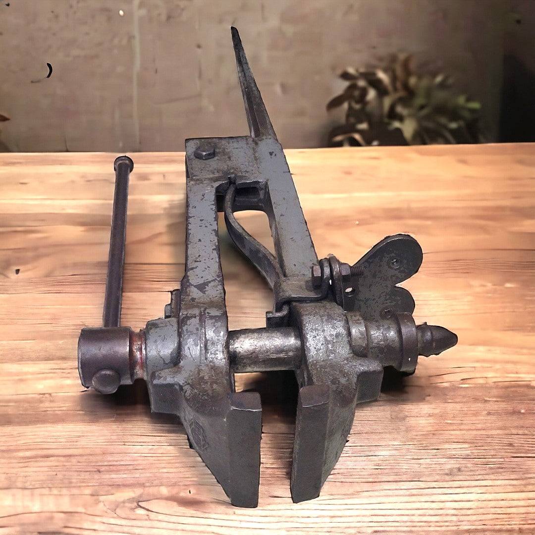 Tornillo de herrero en acero fundido con acabado envejecido, herramienta decorativa robusta para espacios de forja o jardín.