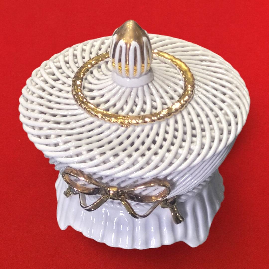Joyero artesanal de porcelana blanca con detalles dorados y diseño trenzado, perfecto para almacenar joyas con estilo en espacios decorativos.