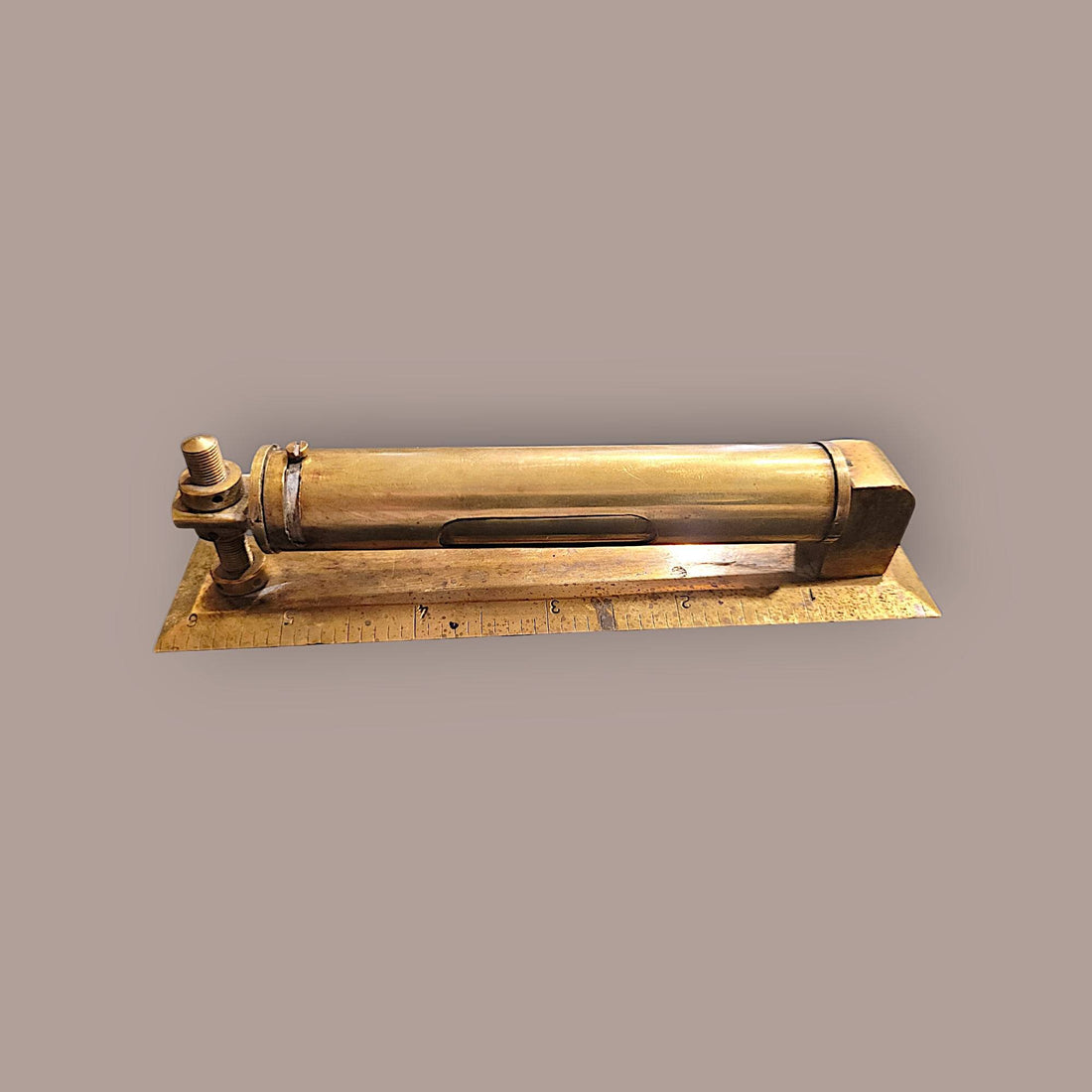 Nivel metálico con funda protectora de 14 cm en latón antiguo, base con escala grabada para mediciones precisas en decoración de interiores.
