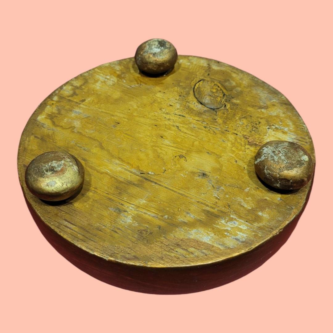 Vista inferior de peana de madera con tres patas redondas, proporciona estabilidad para exhibición de piezas valiosas o figuras.