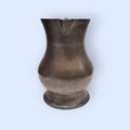 Jarra de peltre de estaño vintage con forma curvada y detalles artesanales, ideal para añadir un toque clásico a la decoración del hogar.