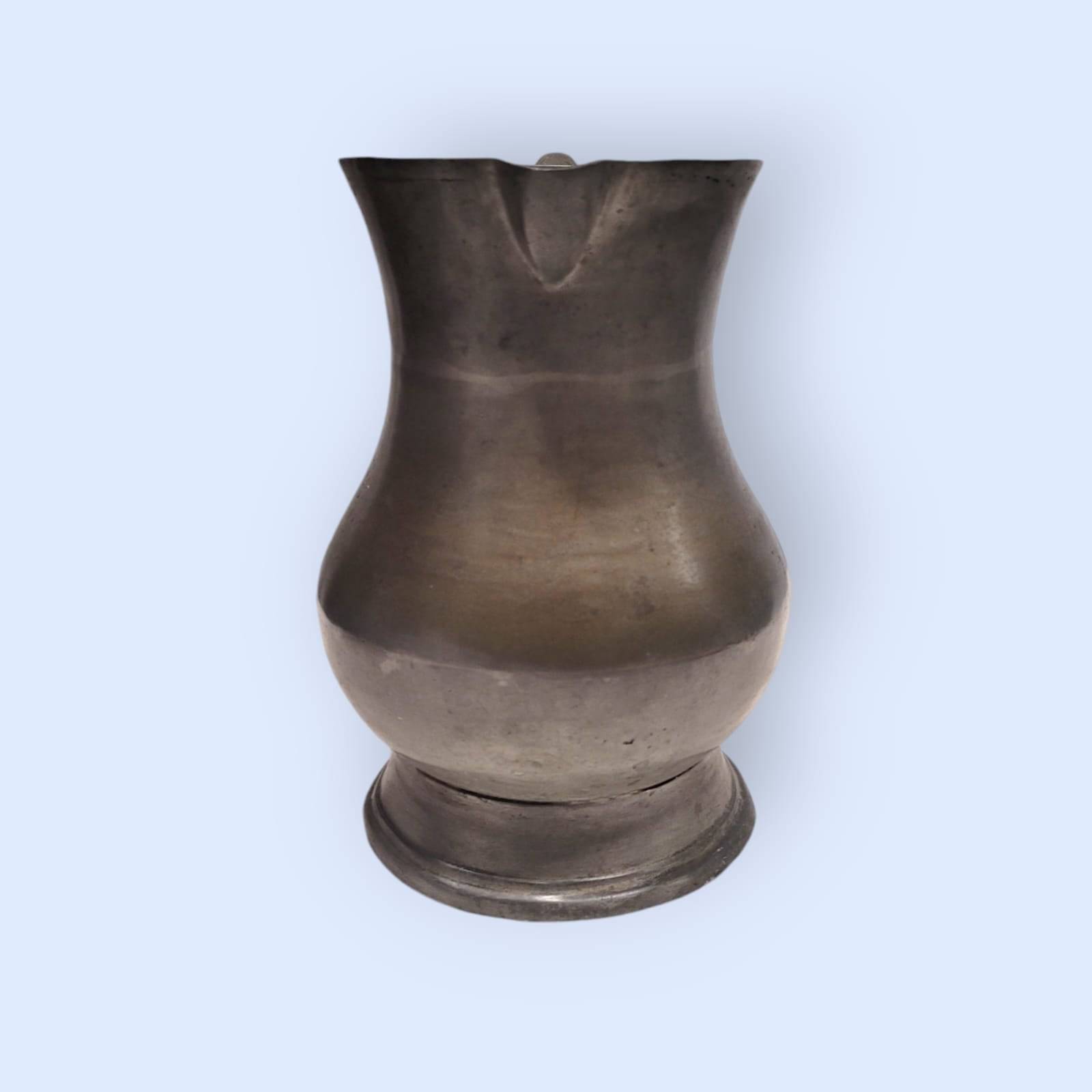 Jarra de peltre de estaño vintage con forma curvada y detalles artesanales, ideal para añadir un toque clásico a la decoración del hogar.