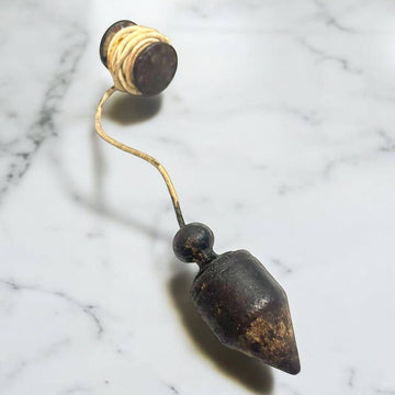 Plomada antigua: herramienta de precisión vertical histórica con cuerda enrollada, ideal para decoración vintage en hogar o jardín.