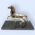 Figura decorativa de caballo en plata con base de mármol negro. Añade lujo y estilo clásico a cualquier espacio del hogar.
