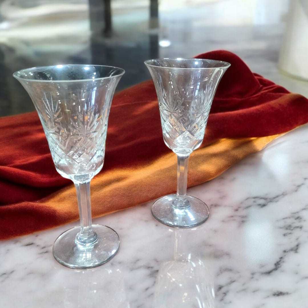 Juego de 2 copas de cristal de Bohemia vintage con diseño clásico, sobre mármol y tela degradada en rojo y naranja, ideal para ocasiones especiales.