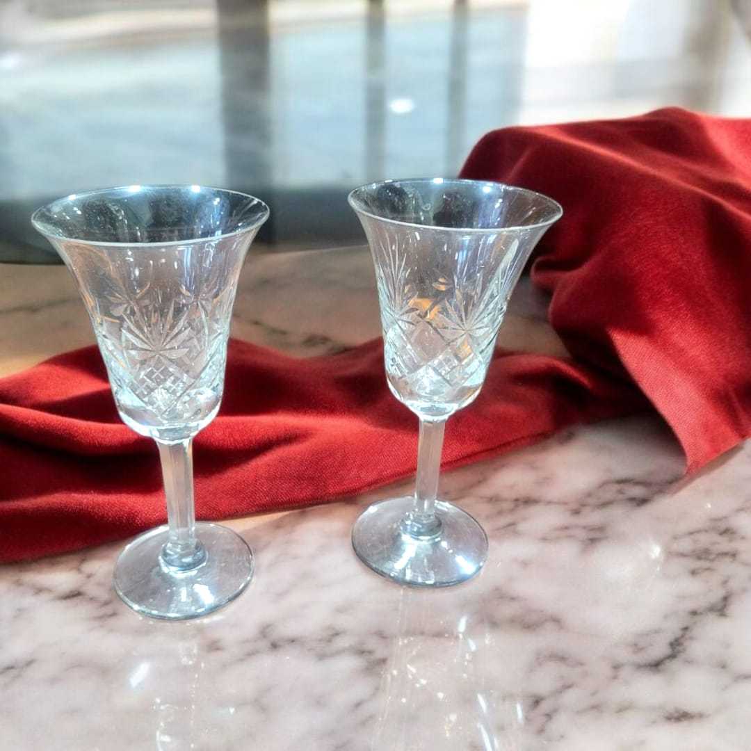 Copas de cristal de Bohemia vintage, juego de 2 elegantes con detalles tallados, colocadas sobre superficie de mármol con tela roja decorativa.