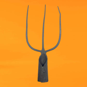 Horca tridente antigua de hierro forjado con tres púas, perfecta para decoraciones rústicas en jardines o interiores vintage.