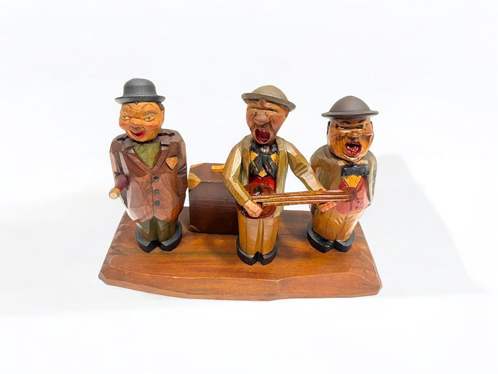 Detalle frontal de figuras de madera tallada con temática musical, integradas con caja de música y accesorios para vino.