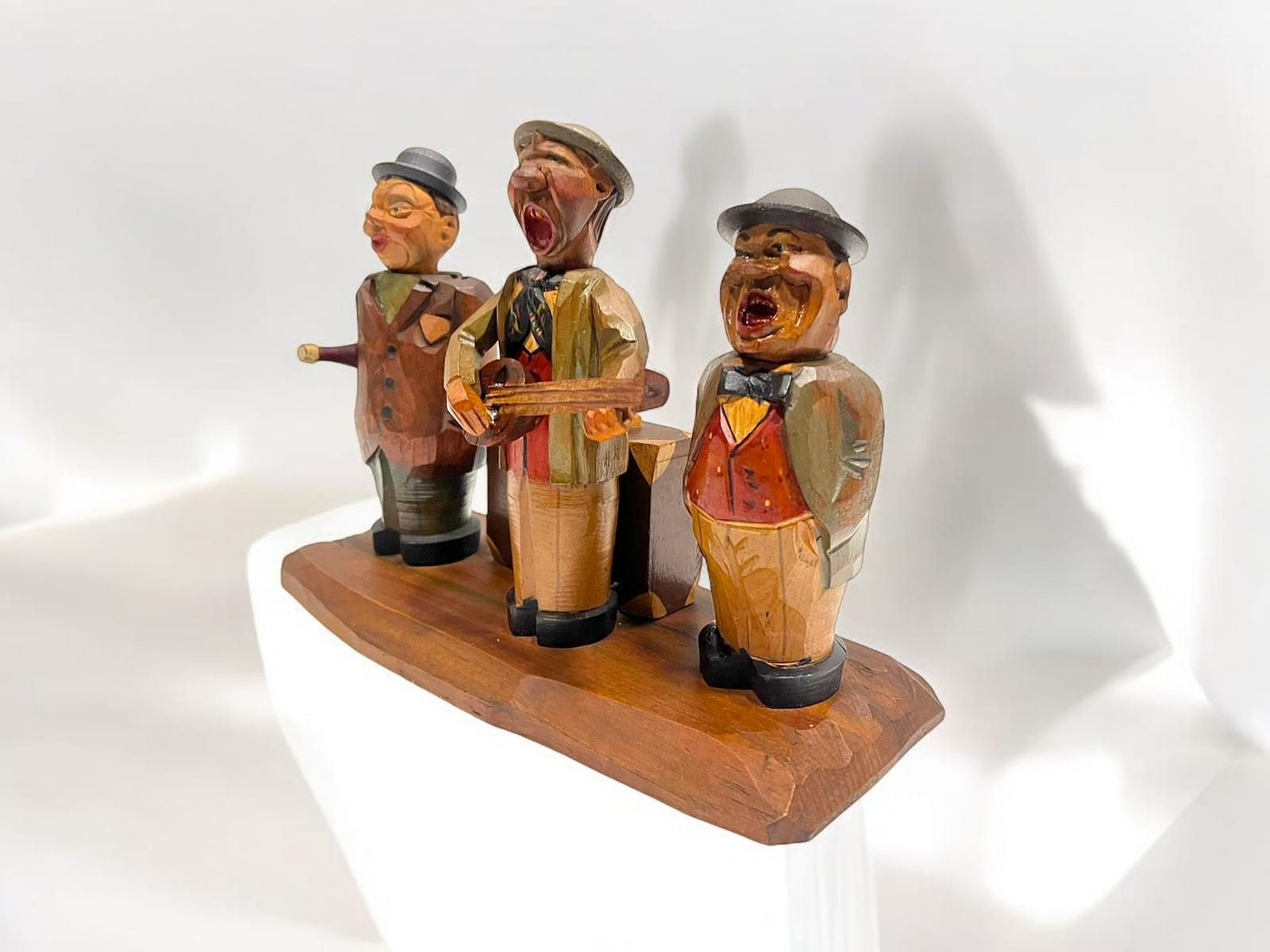 Perspectiva lateral de figuras de madera tallada con caja de música y accesorios para vino, diseño artesanal único.