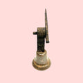 Vista lateral de campanilla de puerta antigua en bronce con soporte de hierro forjado. Decoración clásica para exteriores o interiores rústicos.