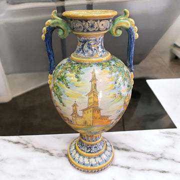 Ánfora de cerámica de Talavera pintada a mano con una iglesia en un paisaje. Diseño artesanal detallado ideal para decoración elegante.
