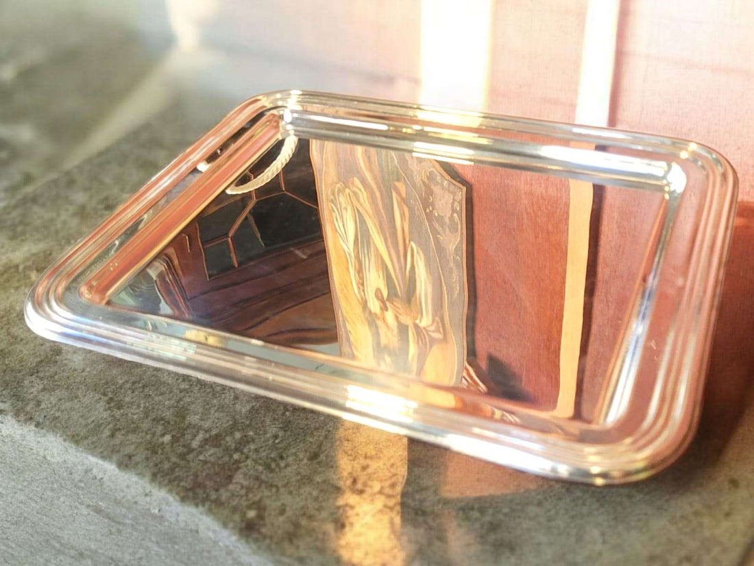 Bandeja de metal plateado con ornamentos elegantes y acabado pulido espejo, ideal para decoración de interiores en estilo clásico.