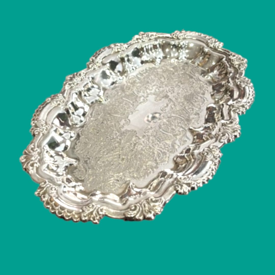Bandeja decorativa de metal plateado con grabados ornamentales y bordes elegantes, ideal para estilo vintage.