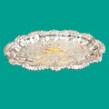 Bandeja ornamental de metal plateado con diseño intrincado y acabado brillante, perfecta para servir o decorar.
