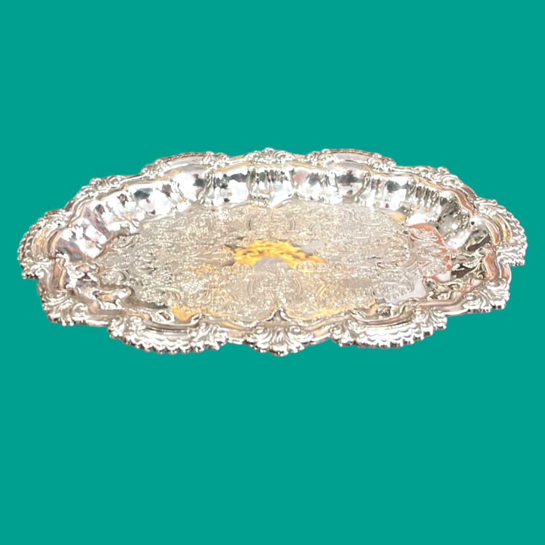 Bandeja ornamental de metal plateado con diseño intrincado y acabado brillante, perfecta para servir o decorar.