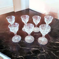 Juego de copas de licor de cristal tallado antiguo sobre mesa de mármol oscuro, diseño clásico ideal para decoración vintage.