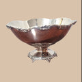 Centro de mesa exclusivo de metal plateado con base ornamentada y diseño sofisticado para decoración del hogar.