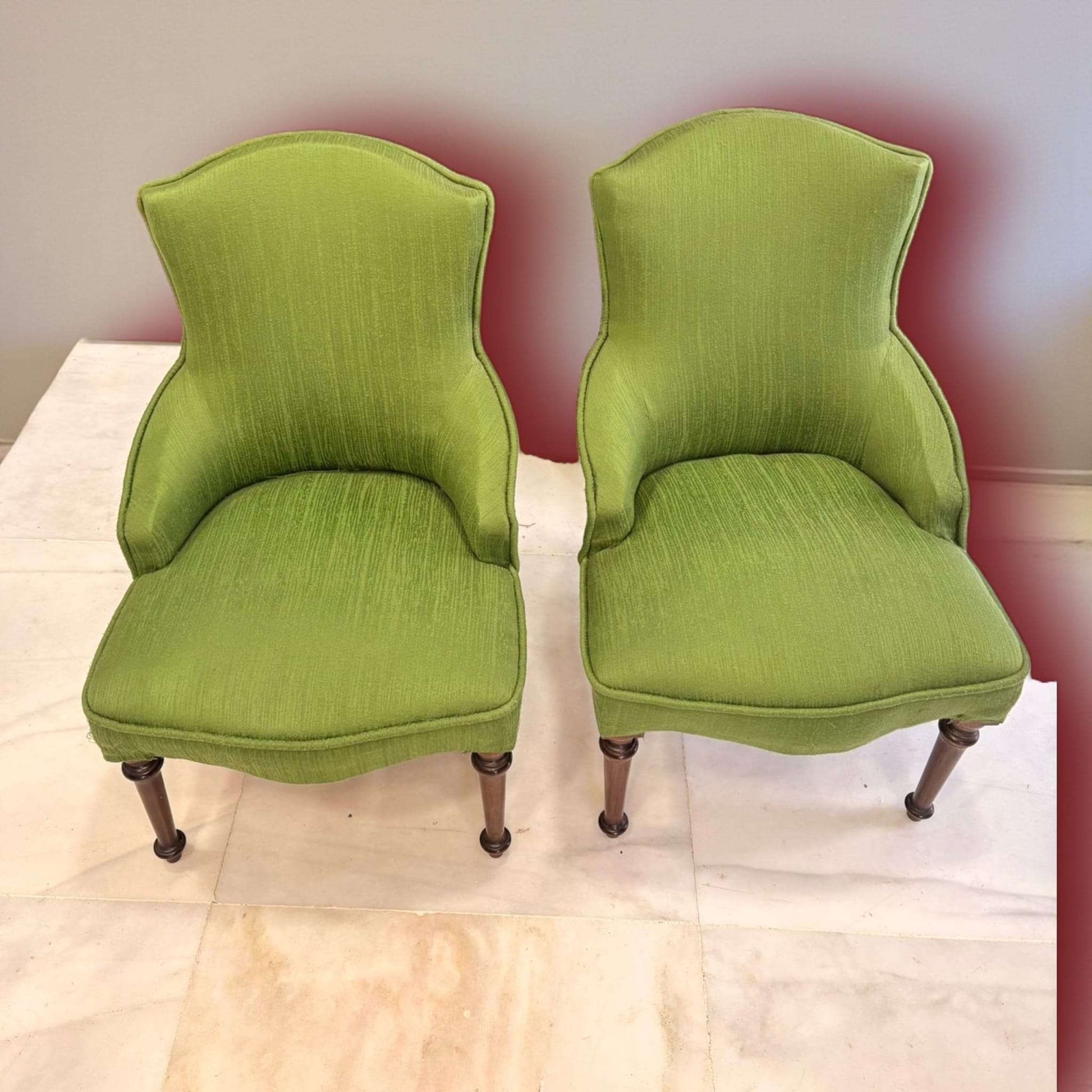 Pareja de descalzadoras tapizadas clásicas con patas de caoba, diseño curvo y acabado en tela verde. Estilo vintage para decoración de hogar.