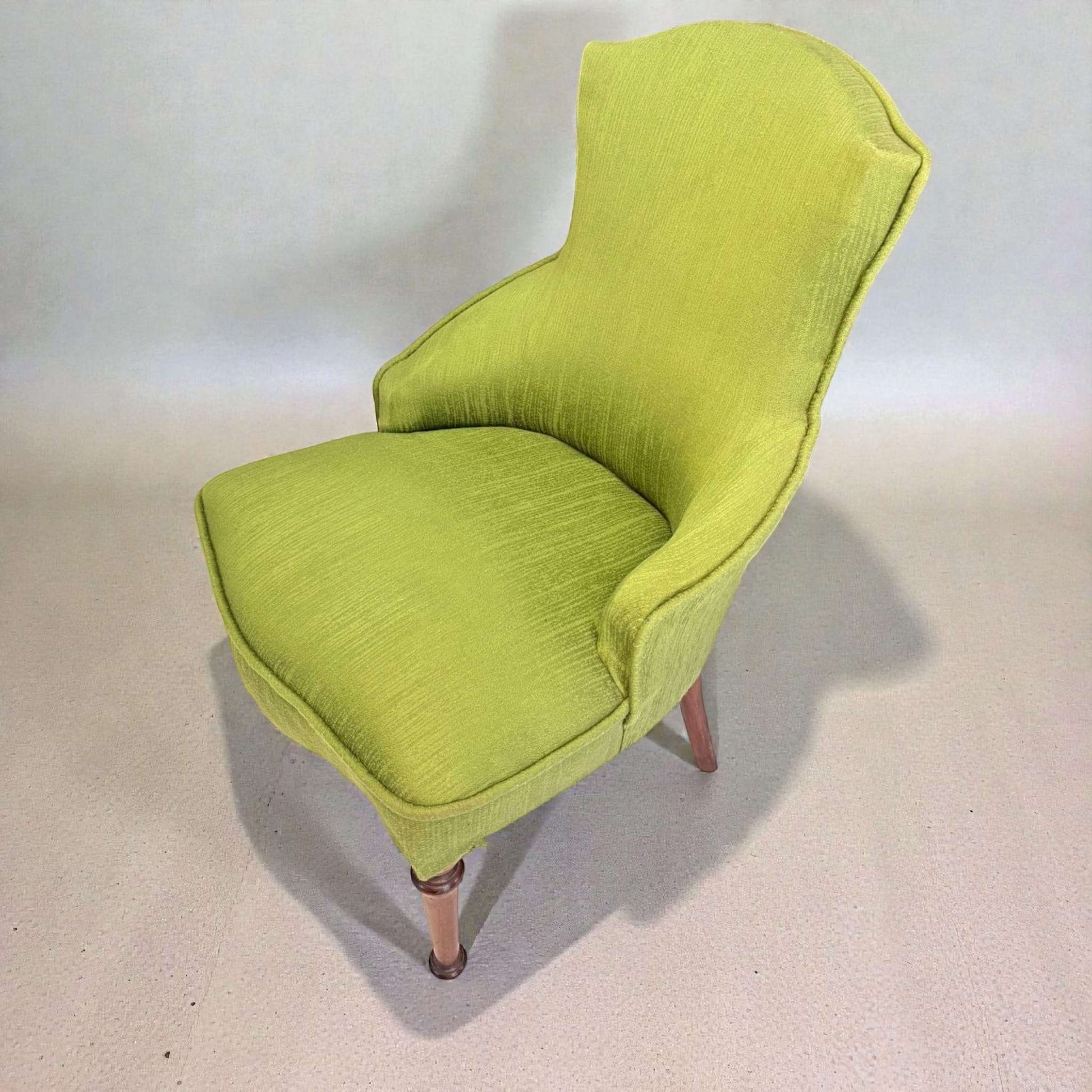 Vista lateral de descalzadora tapizada clásica con respaldo curvo y patas de caoba. Asiento cómodo para dormitorio o entrada.