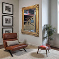 Espejo romántico antiguo con marco de pan de oro original colgado en pared blanca, reflejando interior elegante con decoración clásica.