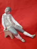 Figura decorativa de porcelana Lladró de un hombre sentado en un banco, con diseño detallado y acabado brillante, ideal para decoración.