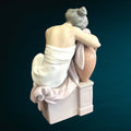 Vista trasera de la figura Lladró 'Soñando Despierta', destacando detalles del vestido y la postura sobre ánfora y pedestal de porcelana.