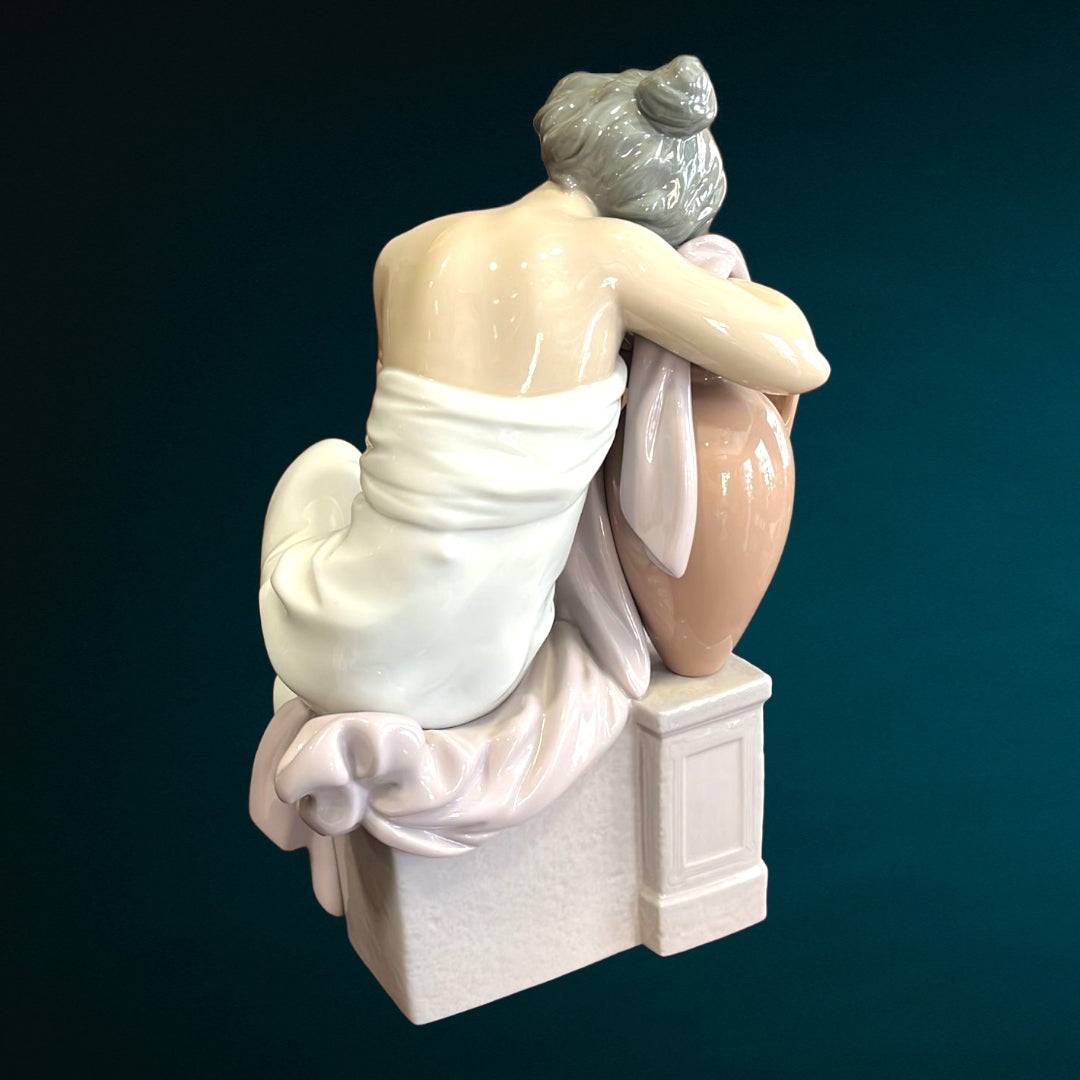 Vista trasera de la figura Lladró 'Soñando Despierta', destacando detalles del vestido y la postura sobre ánfora y pedestal de porcelana.