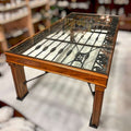 Mesa Reja Comedor con diseño artístico en hierro bajo cristal, estructura robusta de madera, ideal para decoración de comedor con estilo industrial.