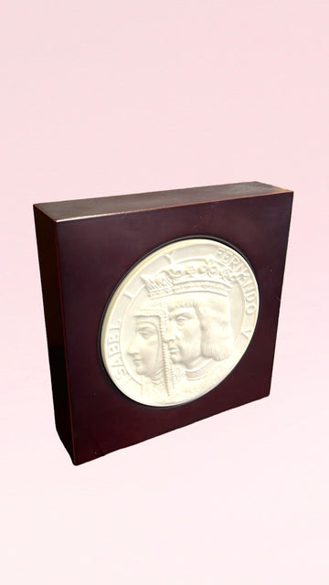 Medallón V Centenario Lladro en relieve con retrato de Isabel y Fernando, montado en base de madera oscura. Edición limitada, ideal para coleccionistas.