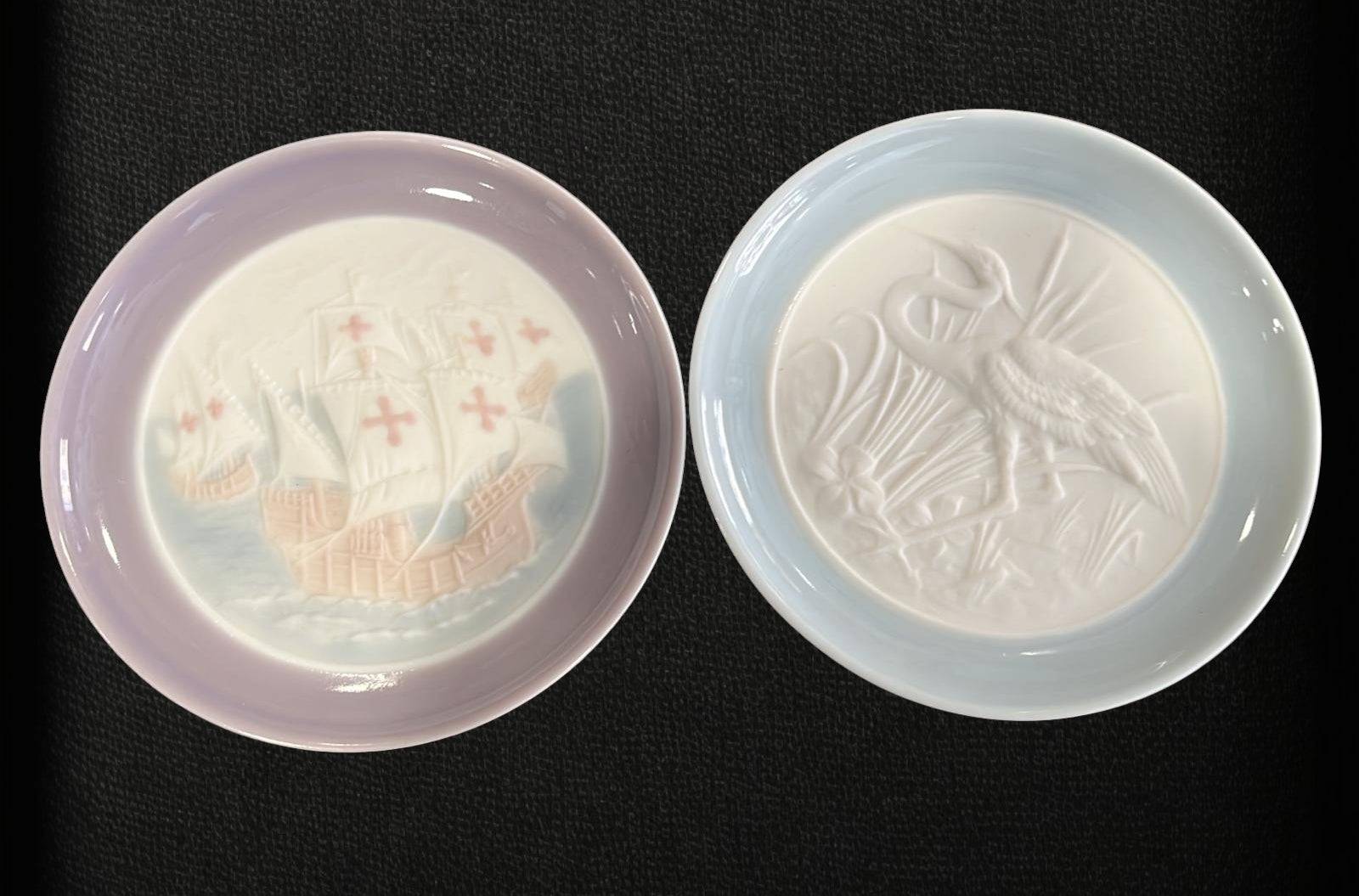 Platos Lladro 1993 con bordes en tonos pastel y detalles en relieve de garza y carabela. Cerámica de alta calidad para decoración elegante.