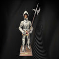 Figura decorativa de armadura toledana con visera abierta, faldón dorado y alabarda, perfecta para ambientes históricos o medievales.