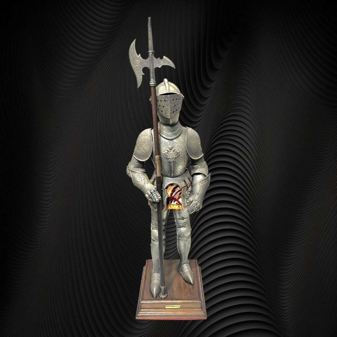 Armadura decorativa estilo toledano con faldón dorado y alabarda, montada sobre pedestal de madera, ideal para decoración de interiores.
