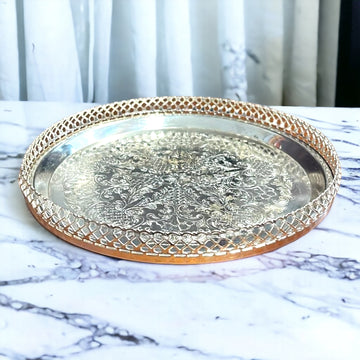 Bandeja Decorada redonda de metal plateado con diseño grabado y borde calado. Ideal para servir o decorar, mide 23xH4 cm.