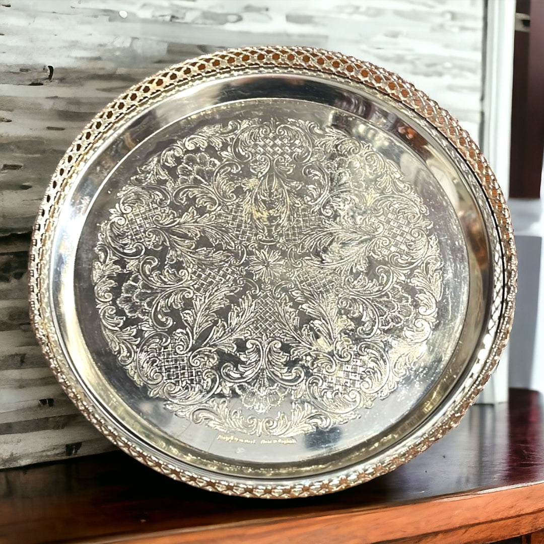 Bandeja Decorada de metal plateado con detalles grabados y borde calado. Perfecta para decoración elegante en el hogar, 23xH4 cm.