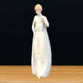 Figura de porcelana Royal Doulton representando a una mujer con vestido blanco y detalles dorados. Ideal para coleccionistas y decoración sofisticada.