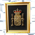 Cuadro decorativo del Escudo de España en metal dorado con fondo negro y marco dorado, ideal para mostrar orgullo nacional en el hogar.