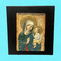 Relieve de la Virgen María y Jesús en resina sobre fondo negro, ideal para decoración espiritual del hogar. Imagen sagrada con detalles dorados.