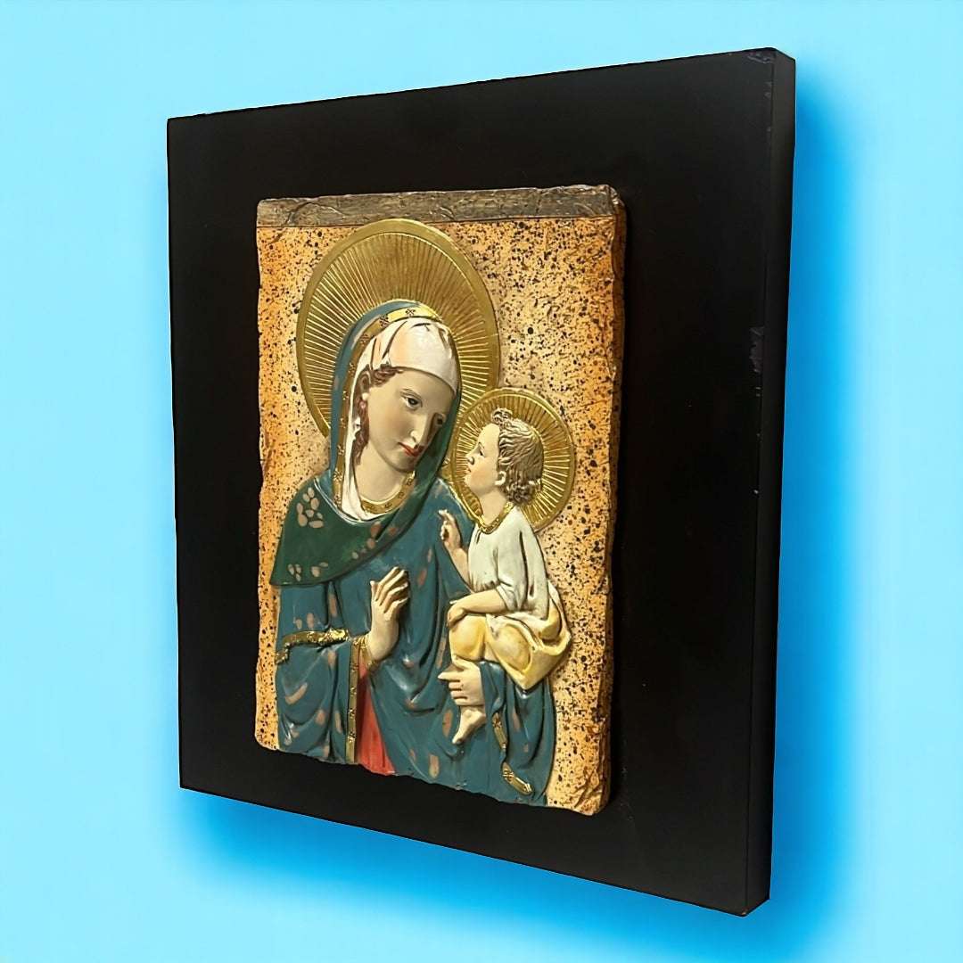 Relieve de la Virgen María y Jesús en resina sobre fondo negro, ideal para decoración espiritual del hogar. Imagen sagrada con detalles dorados.