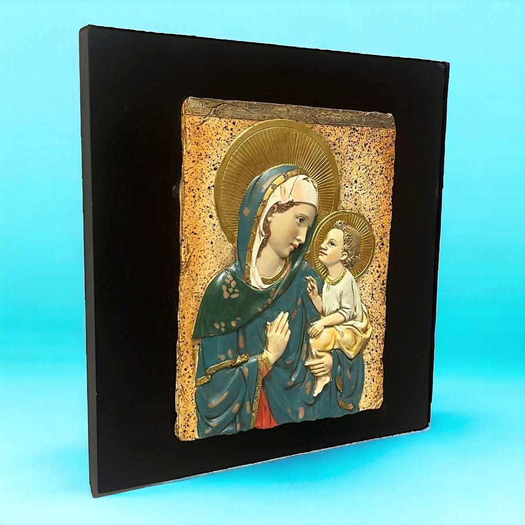 Relieve cristiano en resina de la Virgen y Jesús con halo dorado, sobre base cuadrada negra. Arte sacro para decoración de interiores espirituales.