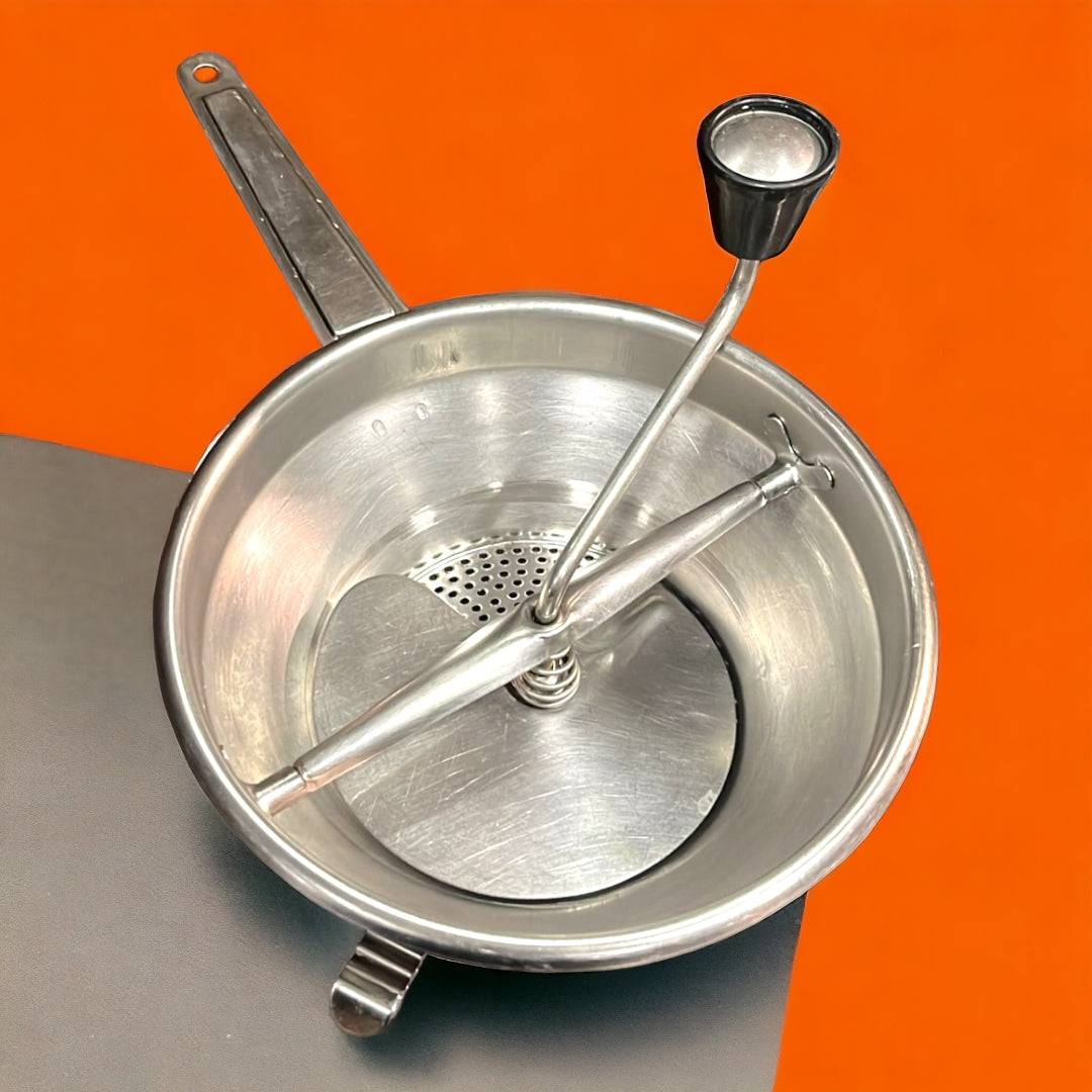 Pasapurés antiguo de aluminio visto desde arriba, mostrando su diseño clásico y funcional. Perfecto para decoración de cocina estilo retro.