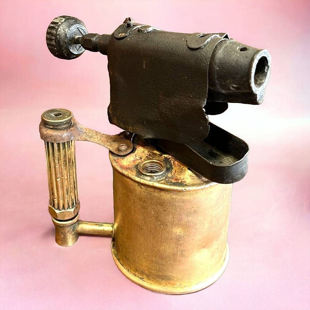 Detalle del mango y boquilla del soplete de fontanero de metal, perfecto para decoración temática industrial o colección de herramientas clásicas.