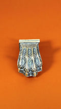 Garra de bronce individual para pata de mesa, con diseño detallado y acabado envejecido, sobre fondo naranja. Ideal para embellecer muebles con estilo.