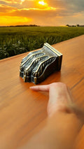 Garra de bronce instalada en una mesa de madera con un paisaje al atardecer de fondo. Aporta un toque de elegancia y distinción a cualquier espacio.