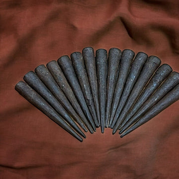 Clavos Sin Cabeza antiguos dispuestos en abanico sobre tela marrón. Ideales para decoraciones rústicas y restauraciones históricas.