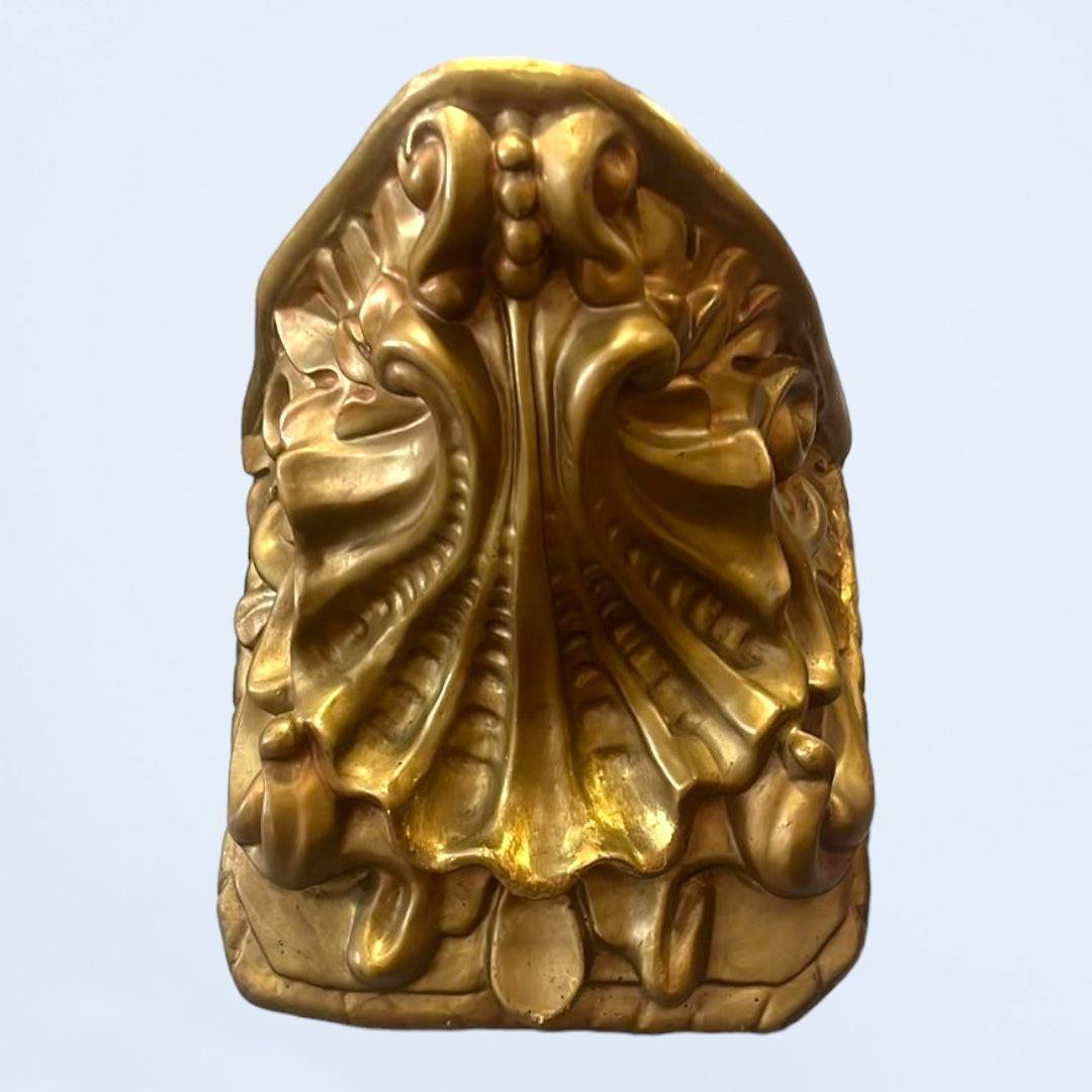 Detalle inferior de peana decorativa en madera antigua policromada, con relieves ornamentales y acabado dorado brillante.