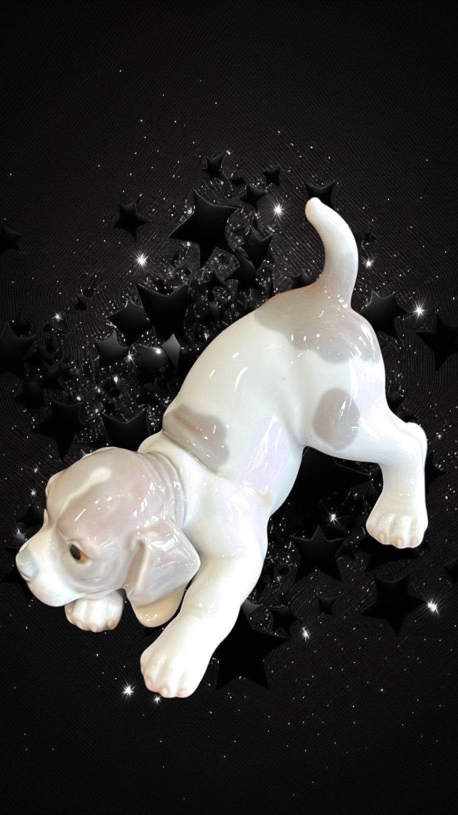 Figura coleccionable Lladró 'Perro Retozón' en porcelana, mostrando detalles artesanales sobre fondo estrellado. Pieza exclusiva de decoración.