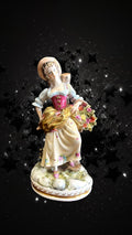 Figura decorativa Dama con Flores en porcelana, con vestido detallado y canasta de flores, perfecta para añadir elegancia a tu espacio.