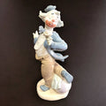 Figura de porcelana Nao-Lladró de payaso con flor en mano, vestimenta azul y beige, pieza decorativa de alta calidad artesanal.