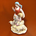 Figura porcelana Señora con Ovejas desde ángulo superior, destaca la expresión facial, el cántaro y las ovejas en relieve. Decoración de alta gama.