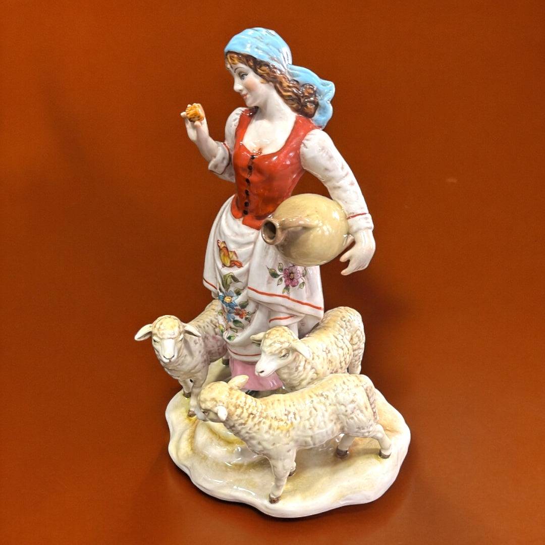 Figura porcelana Señora con Ovejas desde ángulo superior, destaca la expresión facial, el cántaro y las ovejas en relieve. Decoración de alta gama.